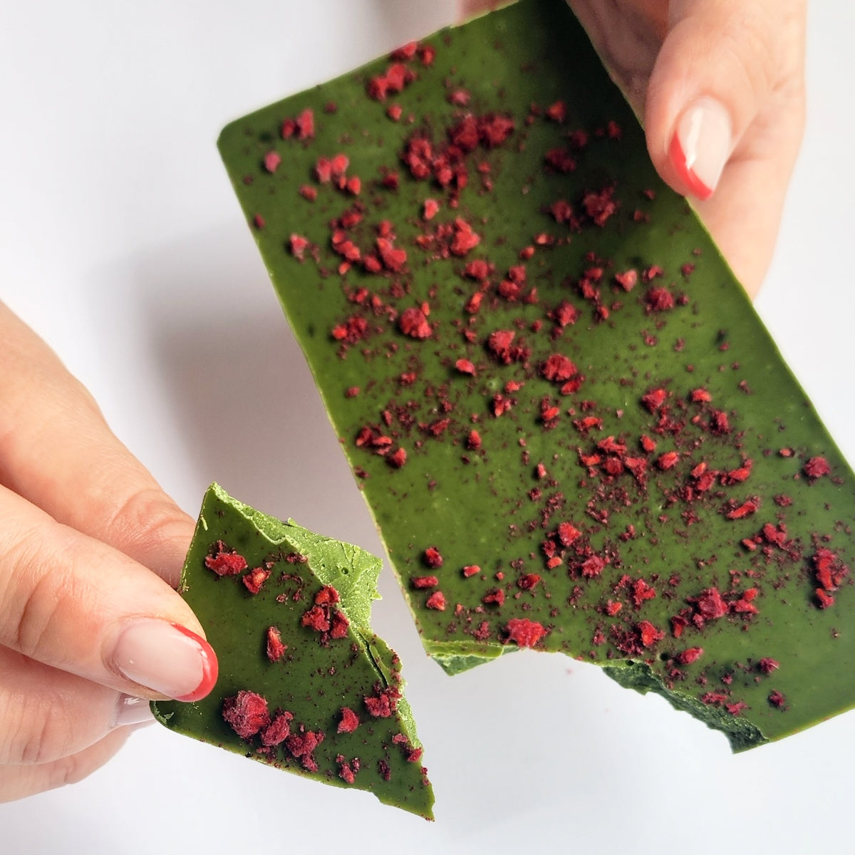 Breaking off a piece of Wabi Matcha Chocolate with a piece in hand ready to eat.